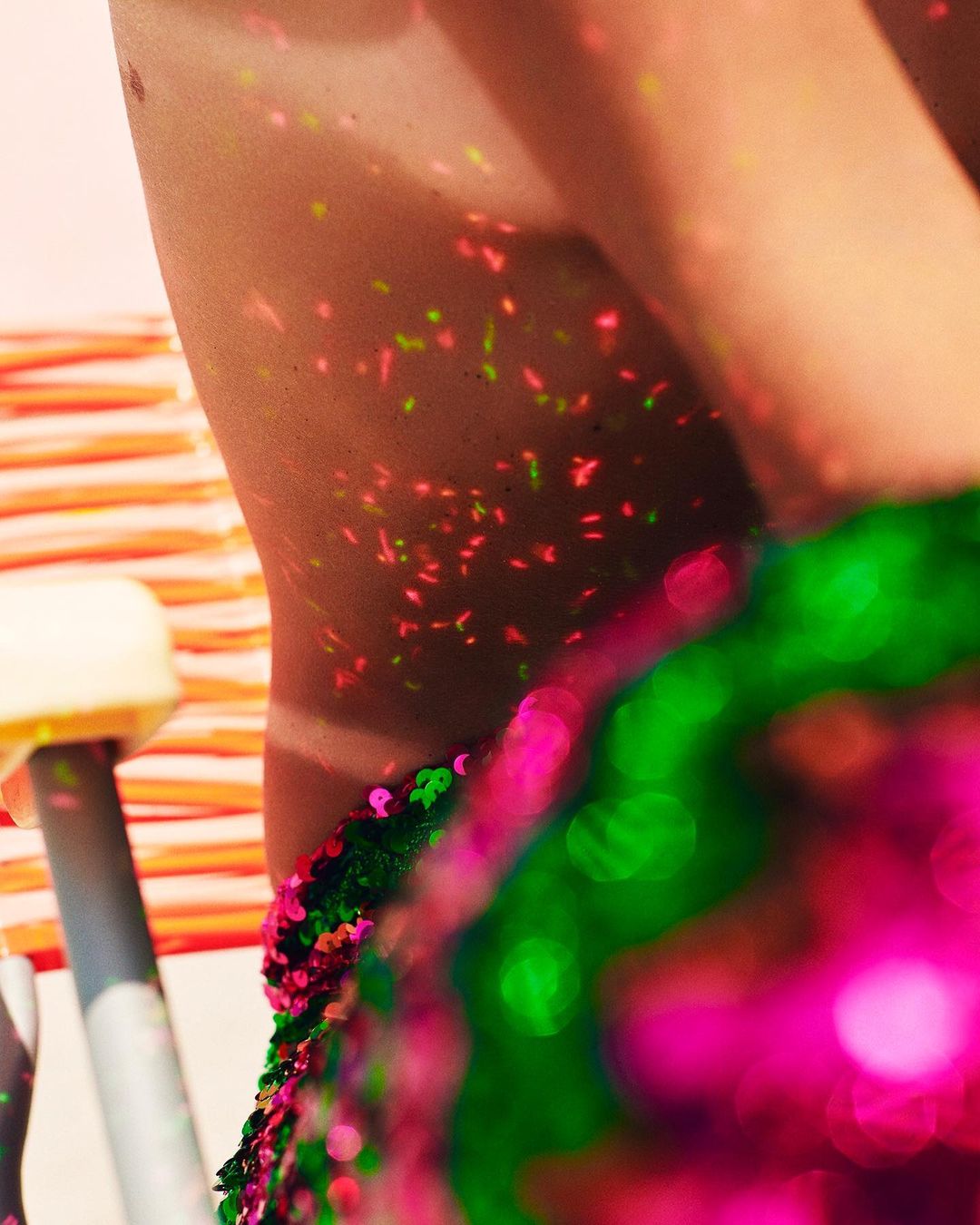Close up of a person with colorful lighting effects and a vibrant sequin skirt, creating a festive and visually striking image.