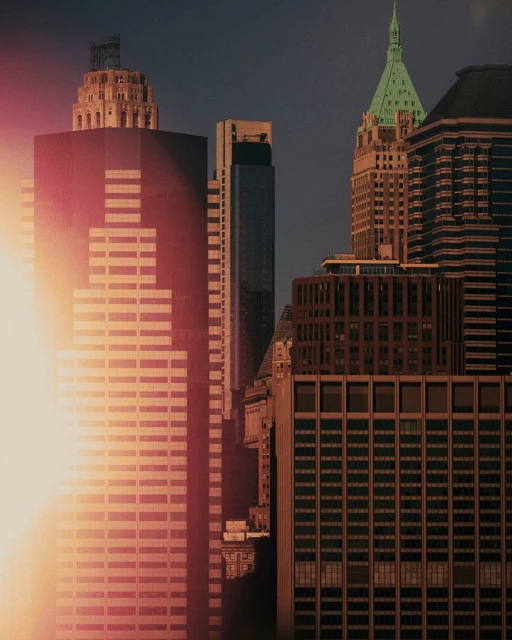 Skyscrapers in an urban cityscape with sun glare, showcasing architectural details and varied heights against a dark sky.
