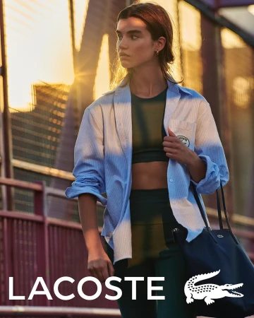 Athletic woman in workout clothes and unbuttoned shirt carrying a tote bag, captured in an urban setting with golden sunlight.