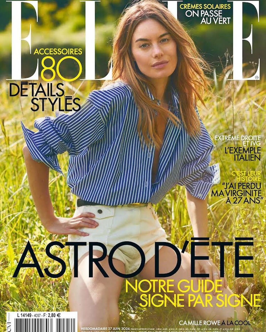 Model in blue and white striped shirt and white shorts posing outdoors in a grassy field for an editorial magazine cover shot.