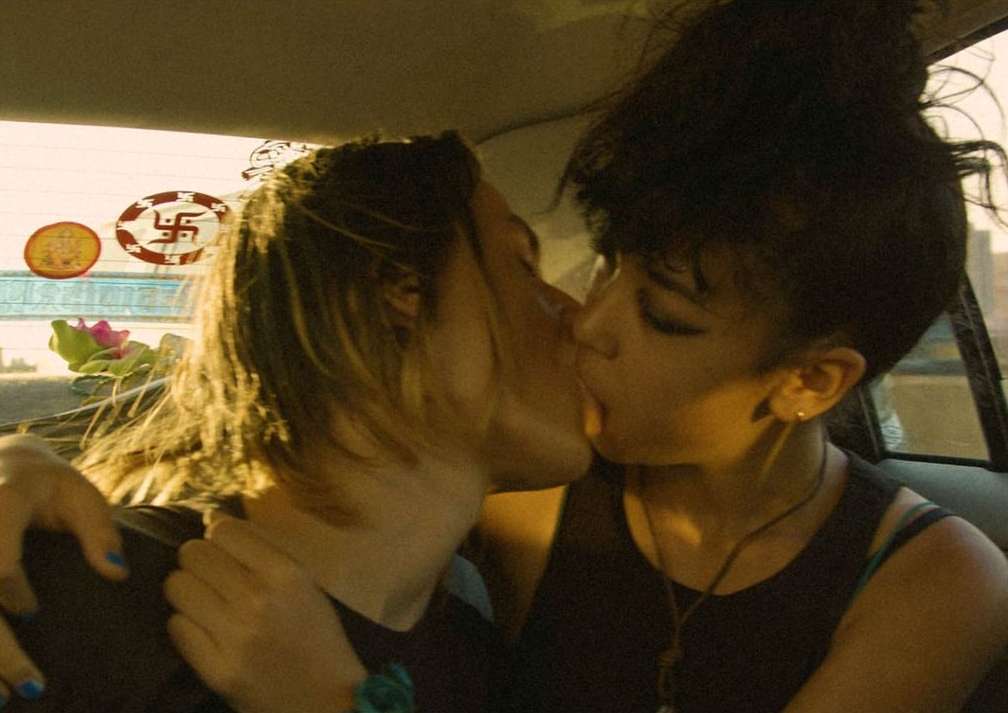 Two people kissing in a car, close-up shot, warm color grading, Swastika stickers on window, romantic lifestyle photography, intimate moment.
