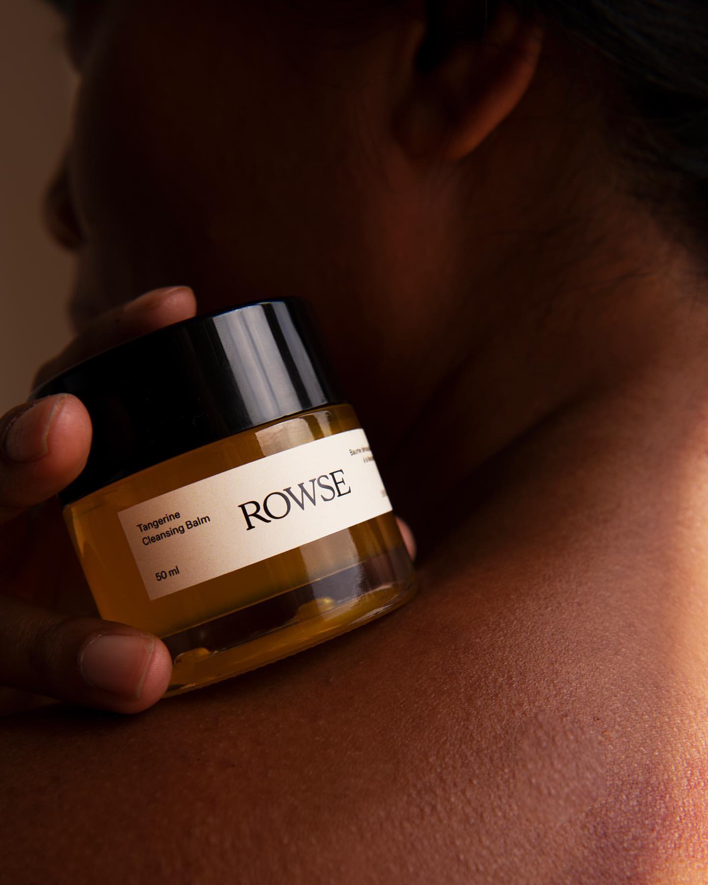 Close-up of a person holding Rowse Tangerine Cleansing Balm, highlighting skincare product and ingredients for beauty and wellness.