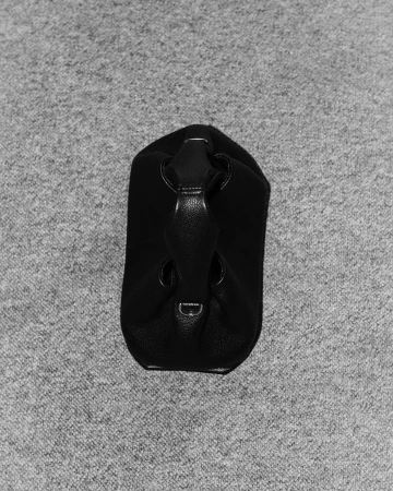 Black leather handbag resting upright on a textured grey carpet background