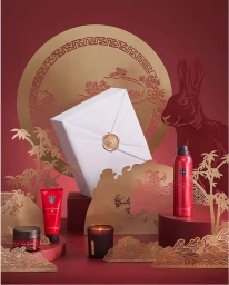 Paper art display featuring a white gift box with gold seal, red cosmetic bottles, a candle, and cut-out golden rabbit motif