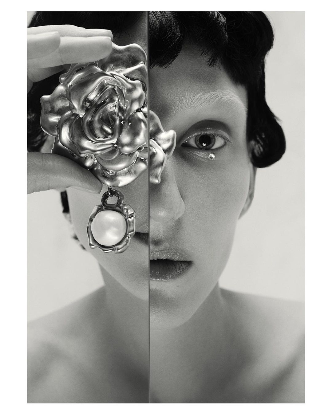 Monochromatic beauty portrait of a woman with short dark hair, adorned with a pearl earring and a large metallic rose embellishment.