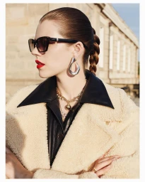 Portrait of a woman wearing oversized sunglasses, a cream shearling coat, and large silver earrings by photographer Lea Nielsen.