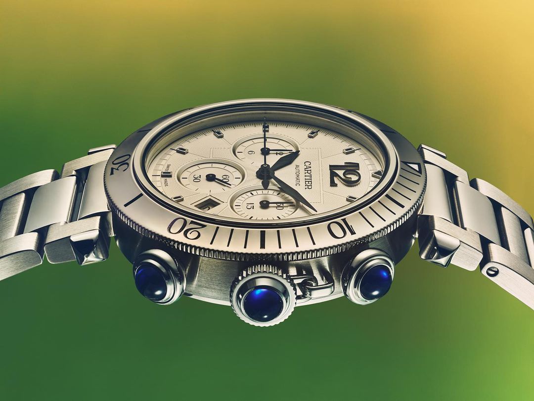 Close-up studio shot of a silver Cartier wristwatch with a round face and metal strap against a background with gradient colors.