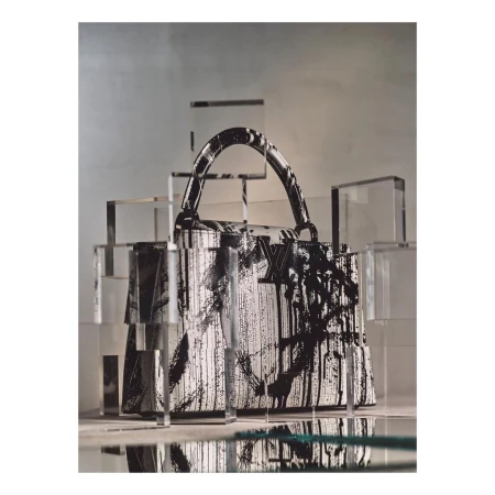 Luxury Louis Vuitton purse with black and white graphic paint, displayed among geometric acrylic cubes in a minimalist fashion shoot.
