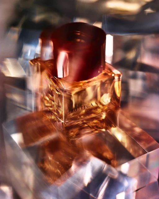 Close-up shot of a rectangular glass bottle of amber-colored liquid with a dark reddish-brown cap, featuring the brand Bottega. 