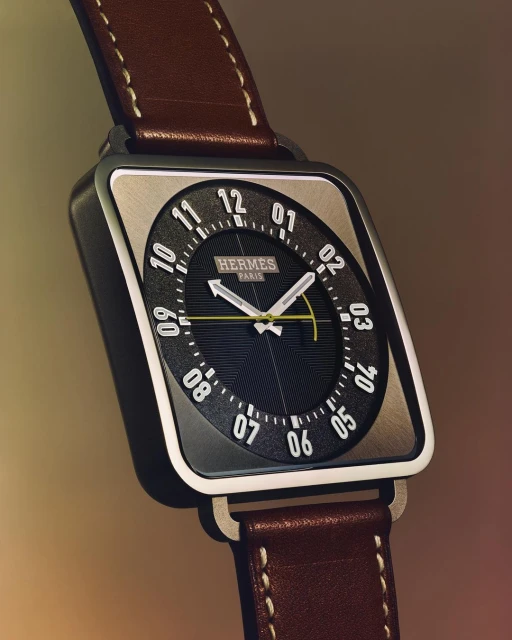 Close-up studio shot of a square-faced wristwatch with a brown leather strap, featuring an analog dial and silver metallic trim.