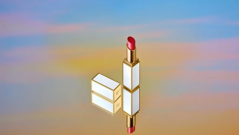 Close-up of red lipstick in gold and white packaging, one standing upright and another lying down, against a colourful background.
