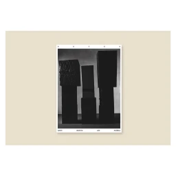 Black and white photographic still life print featuring three dark geometric block objects against a plain background