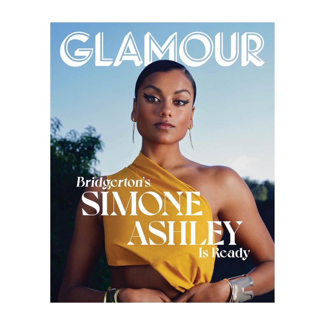 Glamour magazine cover featuring Simone Ashley in a yellow top, jewelry and accessories against a blue sky and trees.
