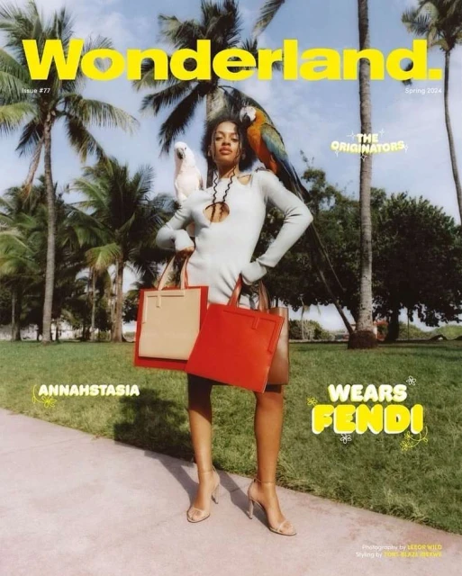 Wonderland Magazine cover featuring a woman in a grey dress with colorful parrots, holding red and tan tote bags in an outdoor setting.
