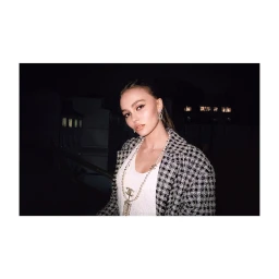 Lily Rose Depp wearing a houndstooth jacket and pearl necklace photographed by Leila Smara at night.