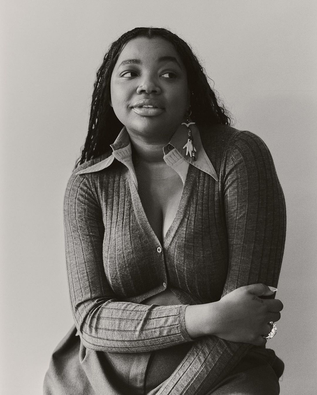 Black and white portrait of an African American woman wearing a cardigan and earrings, looking to the side with a neutral expression.