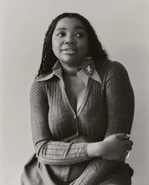Black and white portrait of an African American woman wearing a cardigan and earrings, looking to the side with a neutral expression.