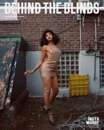 Indya Moore standing outdoors in an alley wearing a beige minidress and heels, photographed by Lelanie Foster