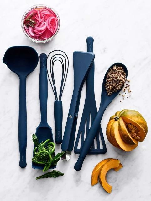 Overhead shot of an arrangement of blue cooking utensils with pickled onions, broccolini, pumpkin pieces, and a spoon full of quinoa.