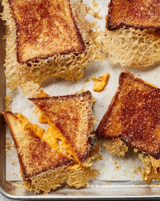 Overhead shot of multiple grilled cheese sandwiches with visible melted cheese on a baking sheet, creating a visually appealing culinary image.