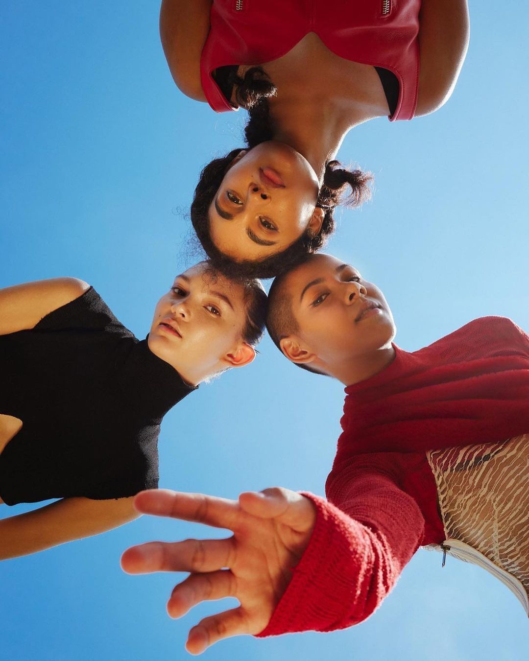 Three diverse women looking down from a low angle against a clear bright blue sky in New York