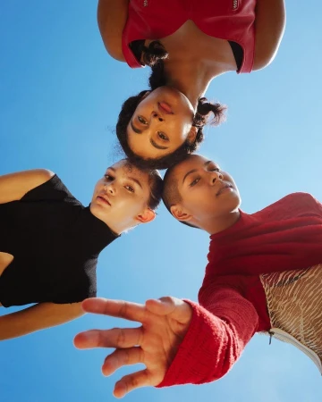 Three diverse women looking down from a low angle against a clear bright blue sky in New York