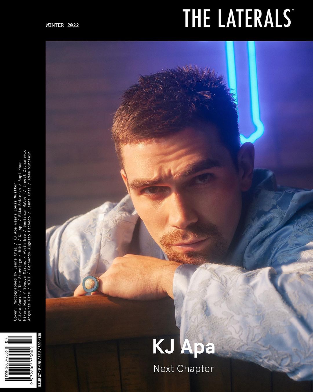 Magazine cover featuring a portrait of KJ Apa in a patterned robe, with blue neon lights in the background and the magazine's title.