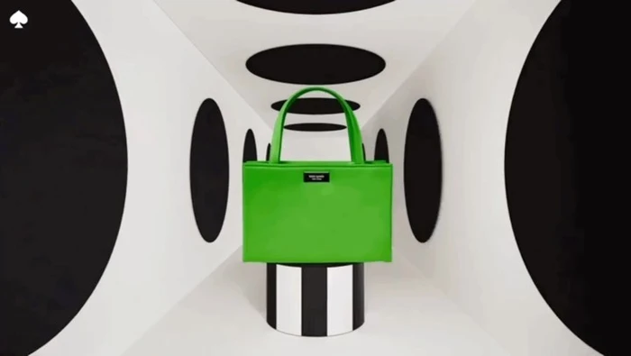 Bright green handbag on a striped pedestal inside a symmetrical white tunnel with black oval cutouts by Leo & Nick