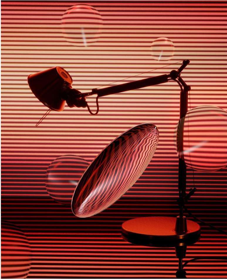Abstract image features a desk lamp with a movable arm, set against a backdrop of red and orange horizontal lines and transparent orbs.