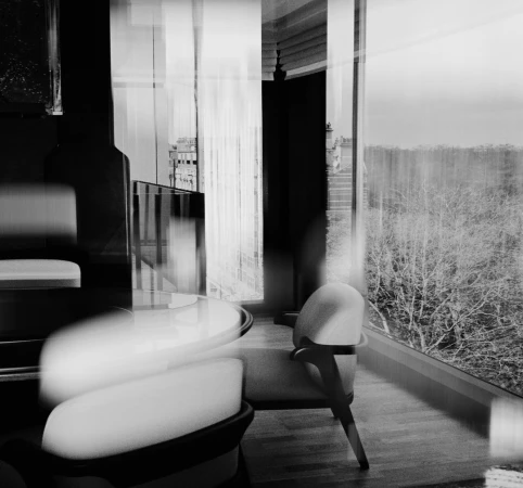 Monochrome interior architectural photograph with motion blur showing a modern chair and large window overlooking trees by Leon Chew