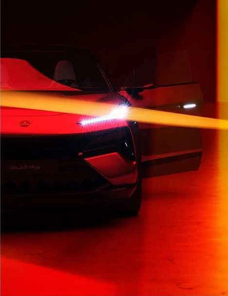 Front view of a black electric car in a studio setting with its door open and a yellow light streak across the hood.