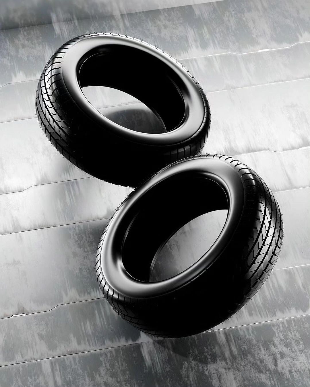 Two black tires are stacked on a gray surface with horizontal lines, showcasing a modern automotive or industrial product display.