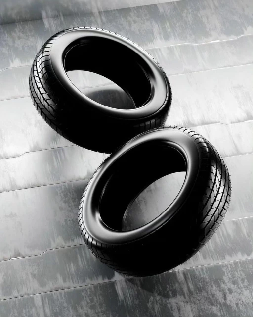 Two black tires are stacked on a gray surface with horizontal lines, showcasing a modern automotive or industrial product display.