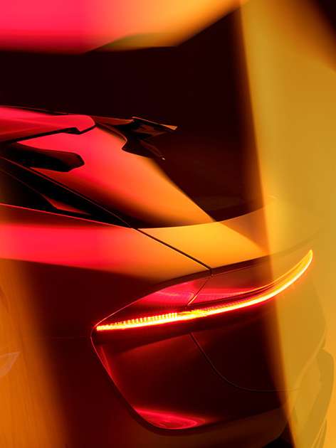 Close-up of the rear of a red and yellow car featuring the taillight, showcasing automotive design and bright color palette.