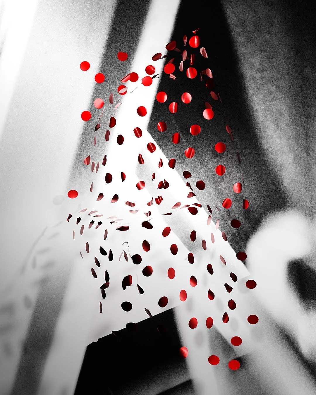 Abstract composition with falling red confetti against a monochrome geometric background. Red dots in dynamic motion.