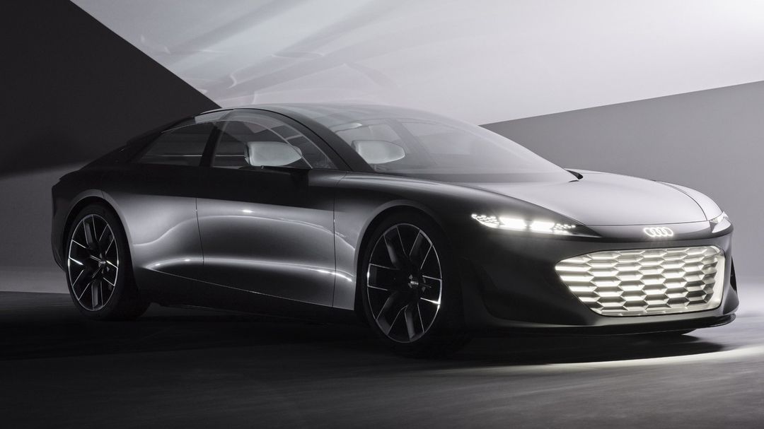 Sleek silver Audi concept car with illuminated grill and black wheels in a dimly lit studio. Automotive design and modern transport.