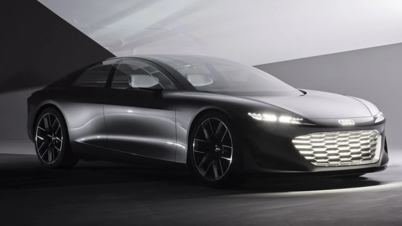 Sleek silver Audi concept car with illuminated grill and black wheels in a dimly lit studio. Automotive design and modern transport.