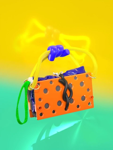 Close-up of an abstract object with an orange, dot-patterned rectangular shape, suspended against a split yellow and green background.