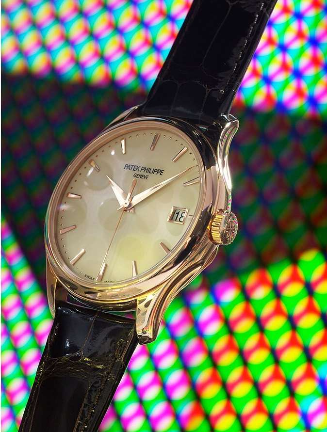 Elegant gold Patek Philippe watch with a black leather strap displayed against a colorful patterned background. Close-up studio shot.