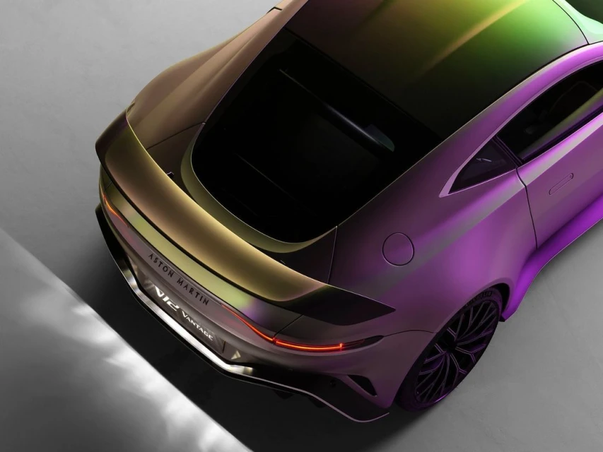 High-angle studio shot of a modern Aston Martin Vantage car with purple, gold, and green iridescent paint in a minimalist environment.
