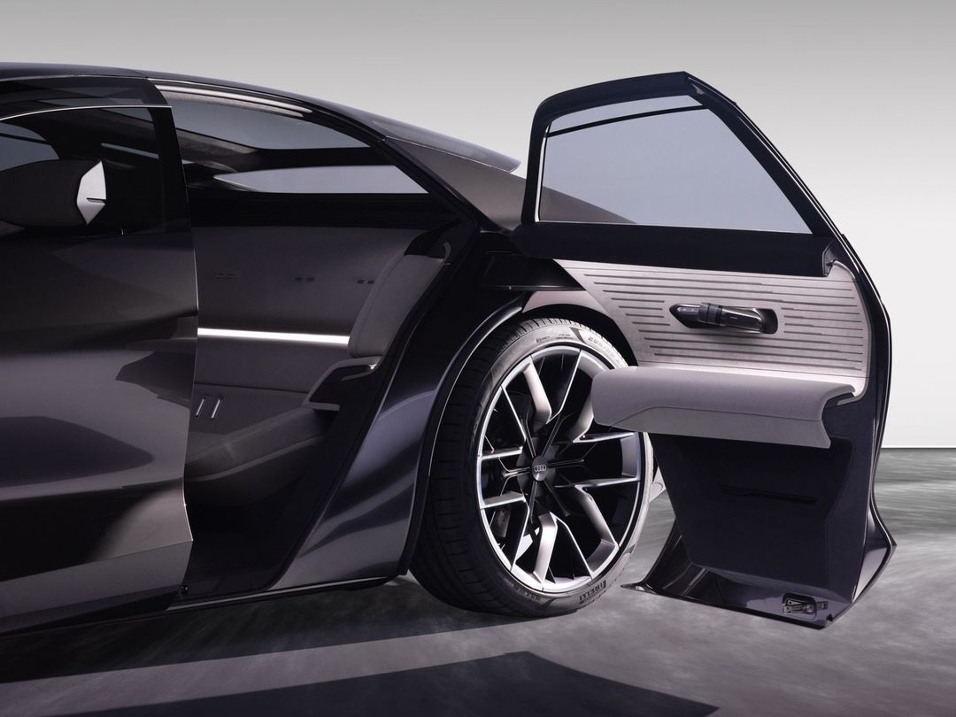 Sleek black car with an open passenger door, showcasing the interior and tire. Automotive design and transportation concept.