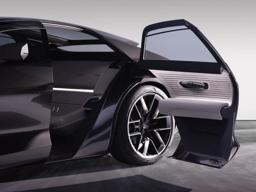Sleek black car with an open passenger door, showcasing the interior and tire. Automotive design and transportation concept.