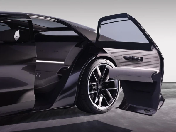 Sleek black car with an open passenger door, showcasing the interior and tire. Automotive design and transportation concept.