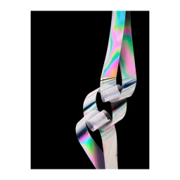 An iridescent metallic ribbon loops and twists against a solid black background, creating a sculptural abstract form.