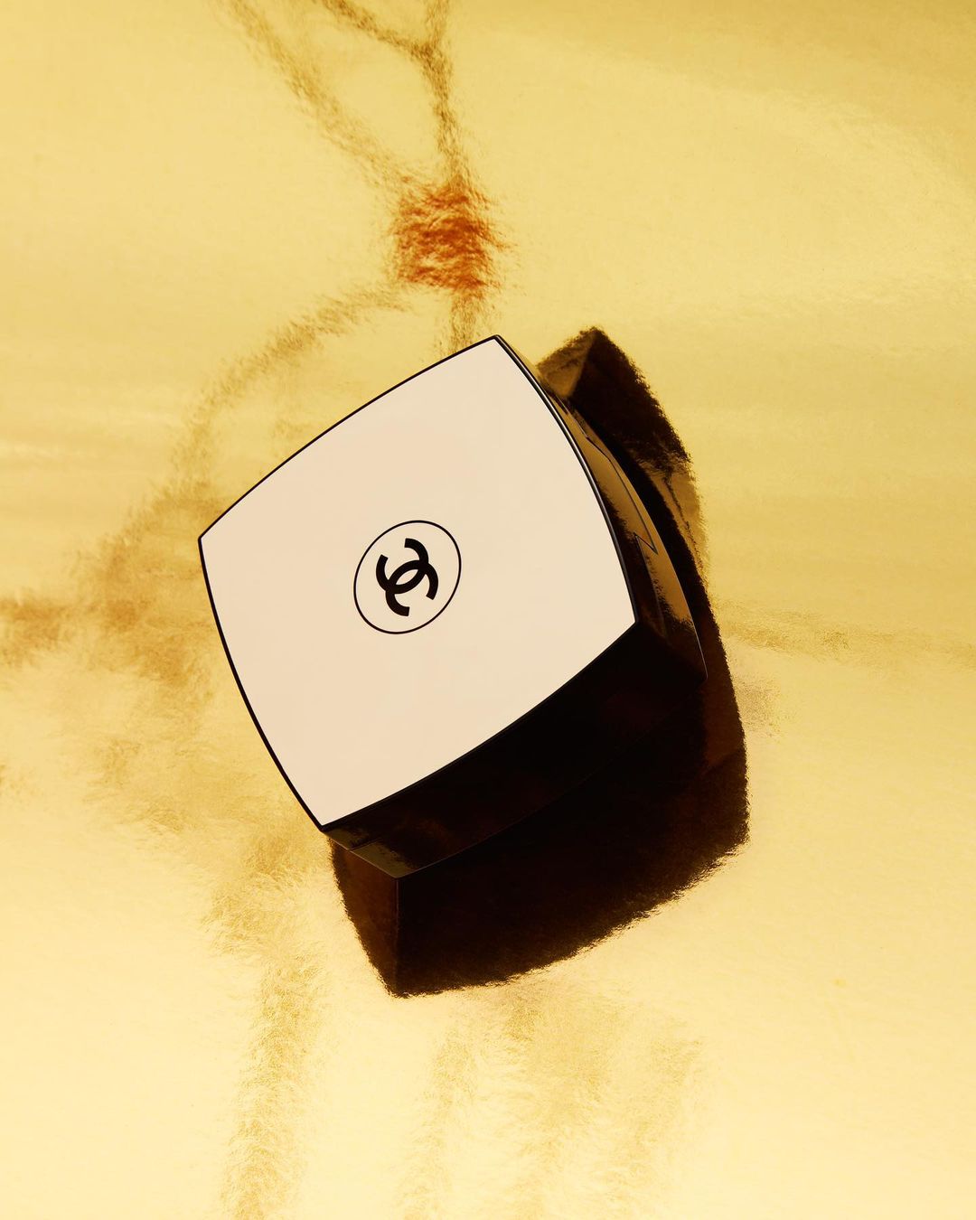 Chanel skincare product against textured gold background. Minimalist beauty shot for cosmetics and skincare advertising.