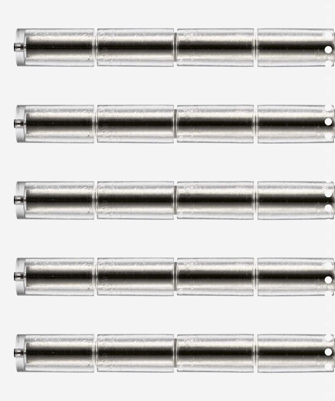 Five rows of AA batteries, showcasing their cylindrical silver metallic bodies with clear plastic wraps, arranged on a white surface.
