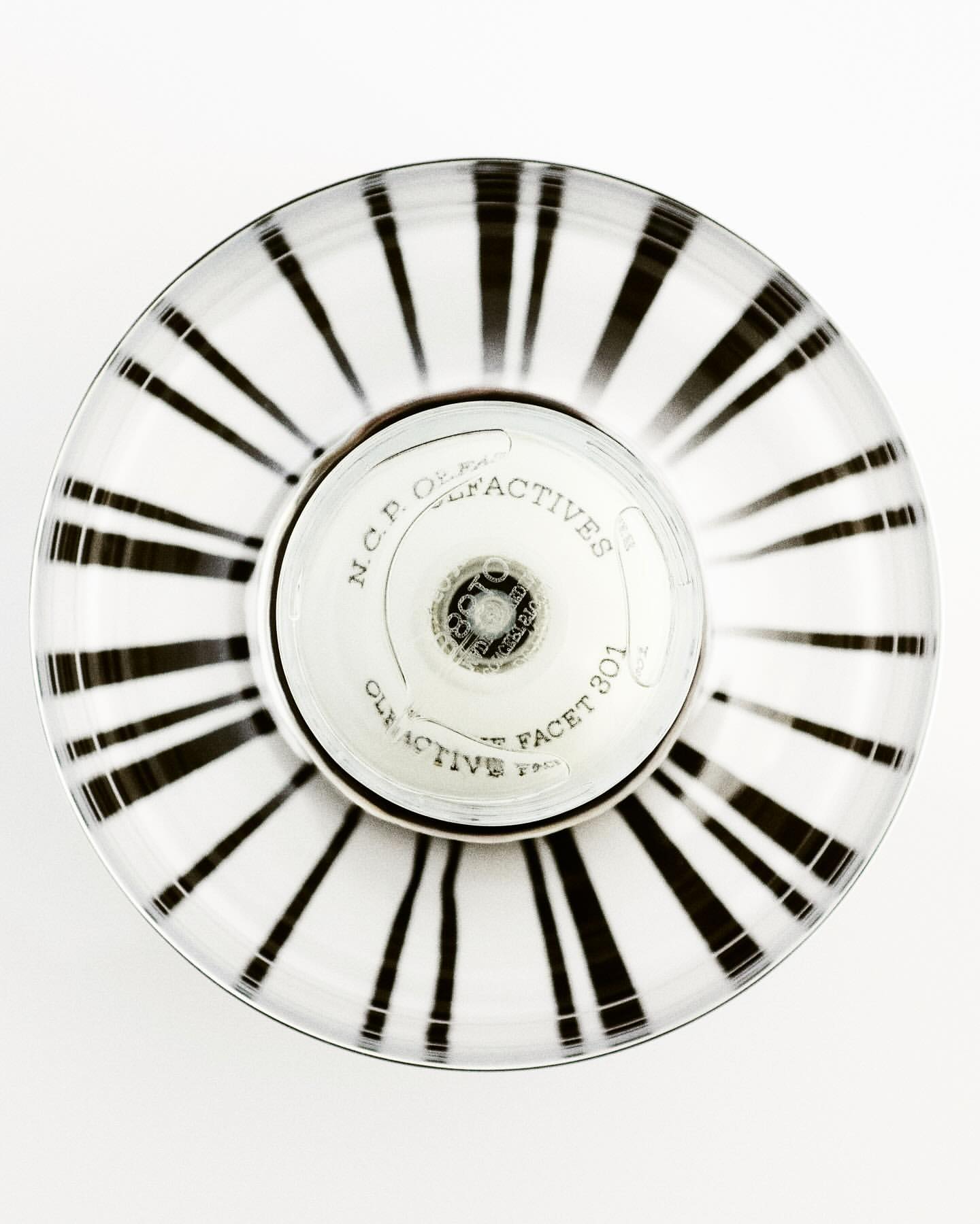 Overhead shot of a striped white and black round container with N.C.P. Olfactives label and silver accents on a plain white backdrop.