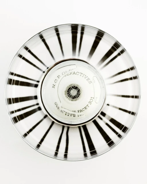 Overhead shot of a striped white and black round container with N.C.P. Olfactives label and silver accents on a plain white backdrop.