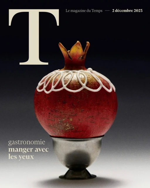 Magazine cover featuring a pomegranate decorated with a delicate white pattern, perched on a silver pedestal, set against a dark background.