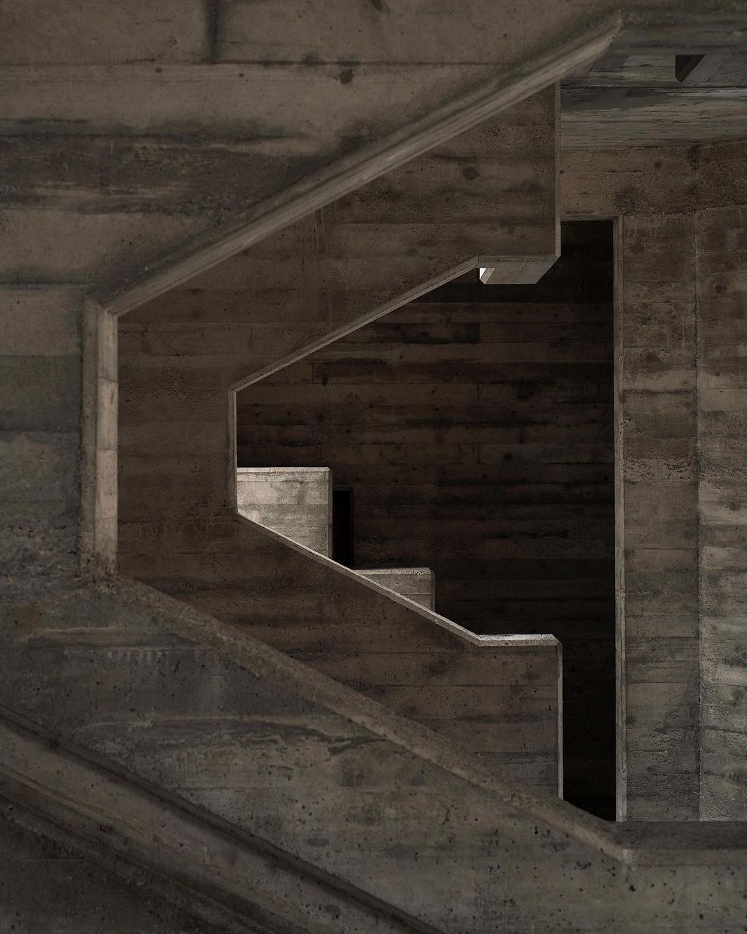 Architectural photo showcases geometric concrete staircase design with light and shadow interplay, highlighting its stark brutalist aesthetic.